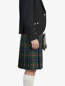 Person wearing a black blazer and green plaid kilt on a white background