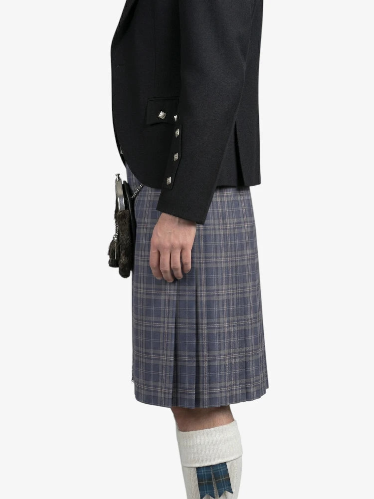 Person wearing a black jacket and plaid kilt on a white background
