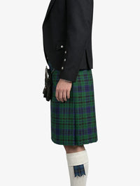 Person wearing a black jacket and green plaid kilt on a white background