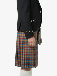 Person wearing a black jacket and plaid kilt on a white background