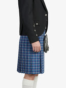 Person wearing a black blazer and blue plaid kilt on a white background