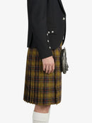 Person wearing a black blazer and plaid kilt on a white background