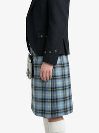 Person wearing a black jacket and blue plaid kilt on a white background