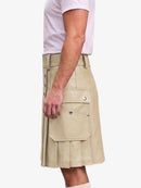 A side view of a person wearing a beige faux-leather kilt with pleated detailing, flap pockets, and silver snap buttons, paired with a light pink t-shirt and white socks.