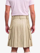A beige pleated mini kilt with side cargo pockets, modeled from the back on a person wearing a light pink t-shirt and white socks against a plain white background.