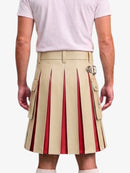 A man wearing a beige pleated kilt with red pleated inserts and silver buckle details, paired with a light pink t-shirt, shown from the back against a light gray background.