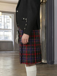 Person wearing a black blazer and red plaid kilt indoors.