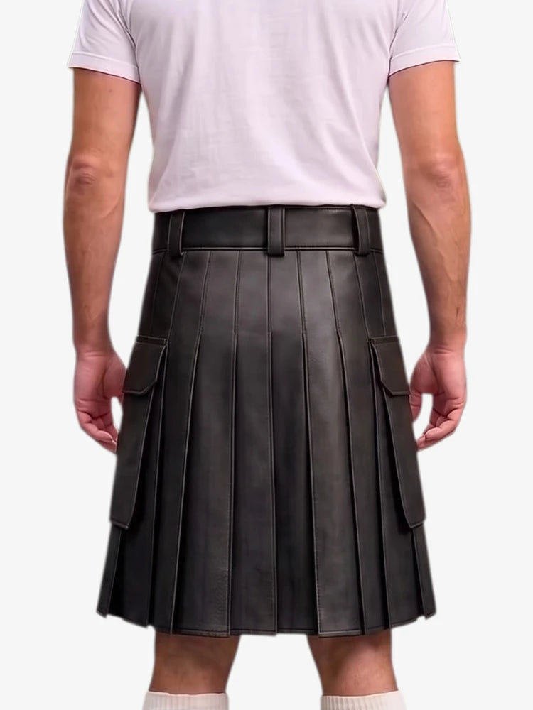 A person shown from the back wearing a black pleated leather kilt with side cargo pockets, paired with a light pink t-shirt and white socks, against a plain light gray background.