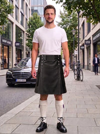 A man stands on a city sidewalk wearing a black leather kilt, white t-shirt, white knee-high socks, and black leather shoes. A black Mercedes-Benz car is parked on the street behind him, with buildings, trees, and a bicycle in the background.