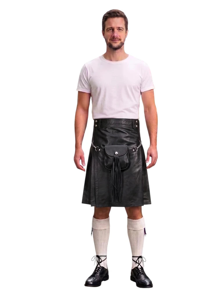 A man modeling a black faux-leather kilt with a matching black waist belt and pouch, paired with a white t-shirt, cream knee-high socks, and black lace-up shoes, against a plain white background.