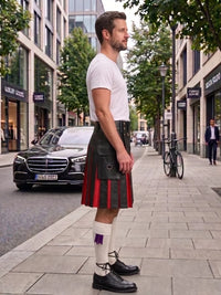 A man standing on a city sidewalk wearing a black leather kilt with red and purple pleats, a white t-shirt, white socks, and black leather shoes. A black Mercedes-Benz car is parked on the street behind him.