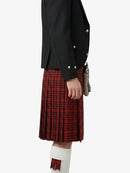Person wearing a black jacket and red plaid kilt on a white background