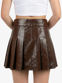 Brown pleated skirt worn by a person on a white background
