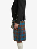 Person wearing a black jacket and plaid kilt on a white background