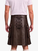 A man wearing a dark brown faux-leather kilt with a lace-up front, side pockets, and pleated detailing, paired with a light pink t-shirt and white socks.