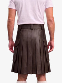 A person shown from the back wearing a dark brown pleated leather kilt with side cargo pockets, paired with a light pink t-shirt and white socks, against a plain light gray background.