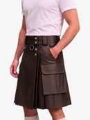 A man wearing a dark brown faux-leather kilt with a wide matching belt, silver-tone hardware, and a large front cargo pocket, paired with a light pink t-shirt.