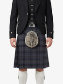 Traditional Scottish kilt with a dark plaid pattern worn by a person on a white background