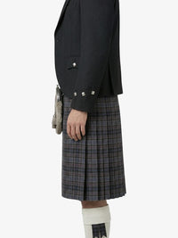 Person wearing a black jacket and plaid kilt on a white background