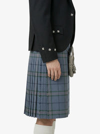 Person wearing a dark jacket and blue plaid kilt on a white background