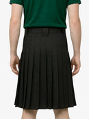 Person wearing a green shirt and black pleated skirt on a white background
