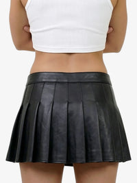 Person wearing a black pleated skirt and white top on a plain background