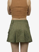 Person wearing a green skirt with zippers and a brown top on a white background
