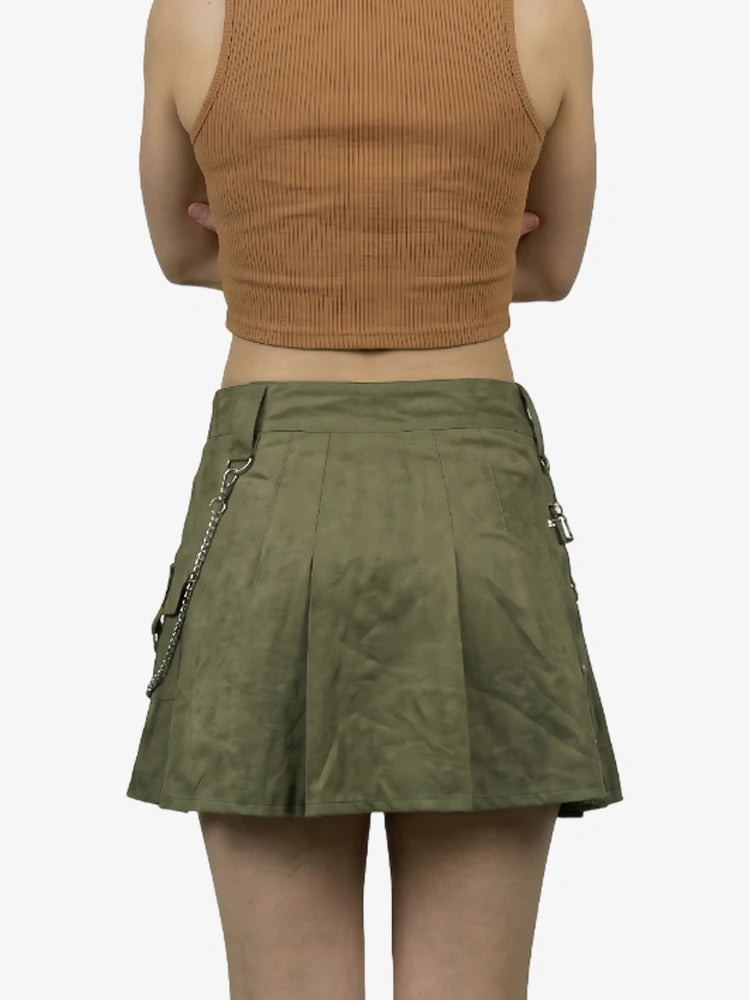 Person wearing a green skirt with zippers and a brown top on a white background