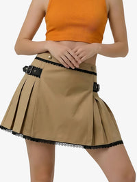 Person wearing a beige pleated skirt with black lace trim and an orange top on a white background