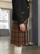 Person wearing a black jacket and orange plaid kilt indoors.