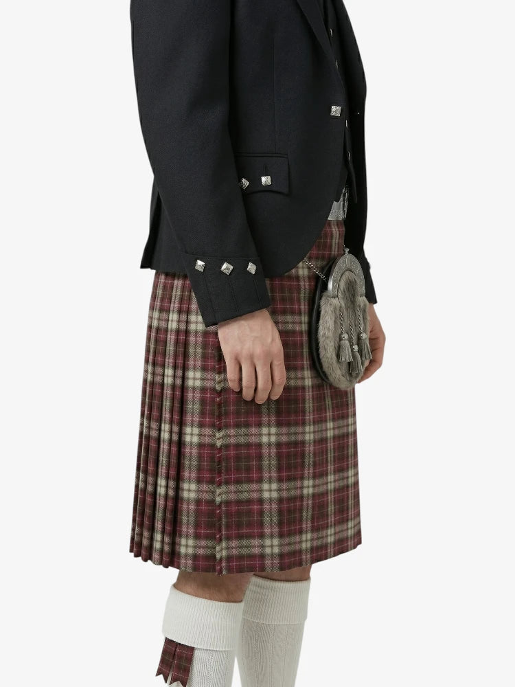 Person wearing a black jacket and red plaid kilt on a white background