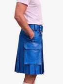 A person wearing a bright blue pleated leather kilt with a front flap pocket, paired with a light pink t-shirt, shown from the waist down against a plain white background.