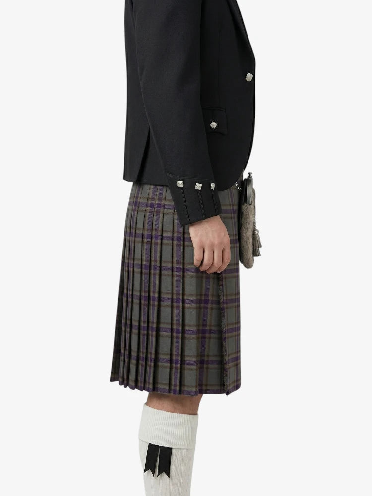 Person wearing a black jacket and plaid kilt on a white background