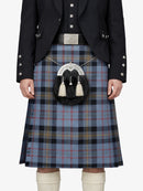Person wearing a traditional Scottish kilt with a tartan pattern on a white background