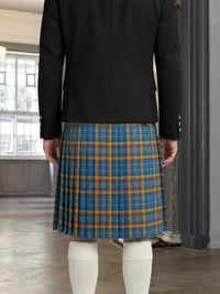 Person wearing a black jacket and blue plaid kilt indoors.