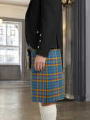 Person wearing a black jacket and blue plaid kilt in an indoor setting.
