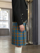 Person wearing a black jacket and blue plaid kilt in an indoor setting.