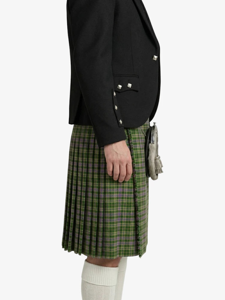 Person wearing a black blazer and green plaid kilt on a white background