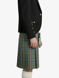 Person wearing a black blazer and plaid kilt on a white background