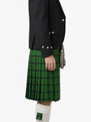 Person wearing a green plaid kilt with a black jacket on a white background