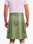 A person shown from the back wearing a sage green pleated leather kilt with a central lace-up closure and side cargo pockets, paired with a light pink t-shirt and white socks.