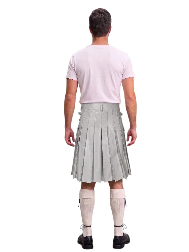A man shown from the back wearing a light gray pleated kilt, a pale pink t-shirt, cream-colored knee-high socks, and black shoes, set against a plain white background.