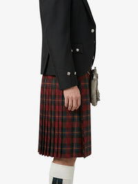 Person wearing a black jacket and red plaid kilt on a white background