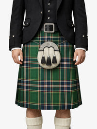 Person wearing a traditional Scottish kilt with a green plaid pattern, black jacket, and white socks.
