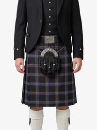 Person wearing a black jacket, plaid kilt, and white knee-high socks on a white background