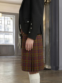 Person wearing a black jacket and plaid kilt in an indoor setting