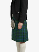 Person wearing a black blazer and green plaid kilt on a white background