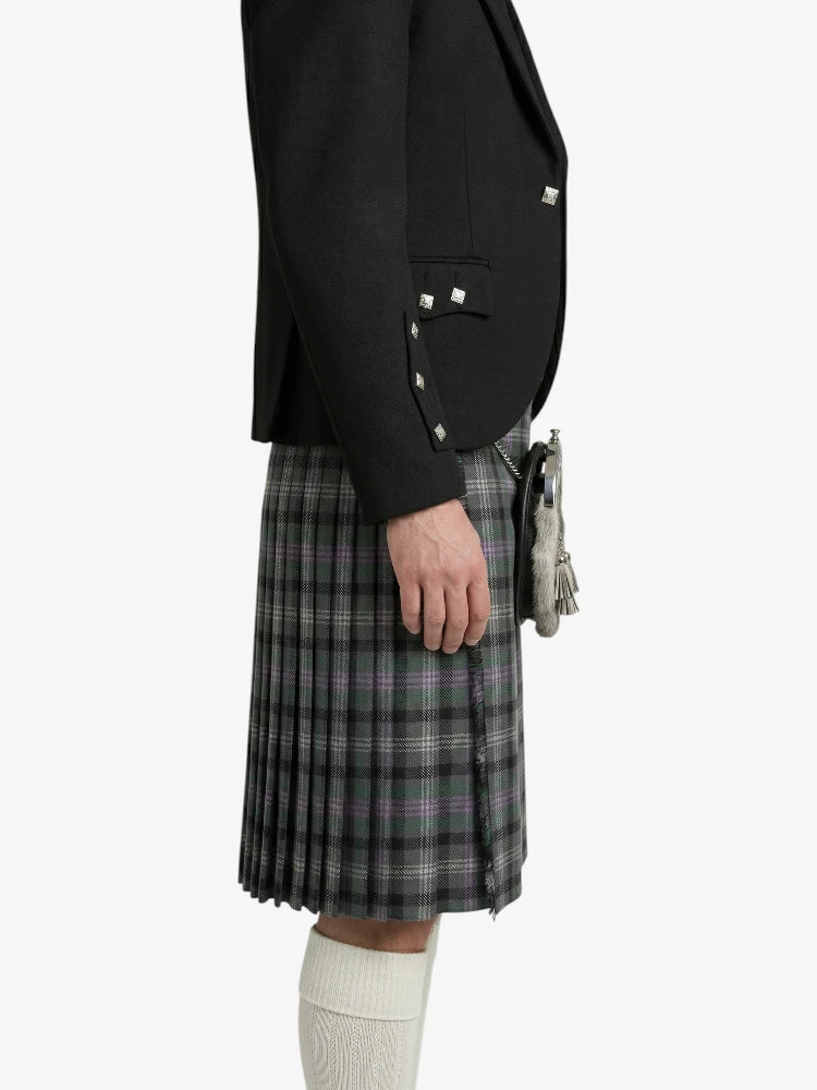 Person wearing a black blazer and plaid kilt on a white background