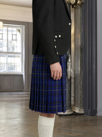 Person wearing a black jacket and blue plaid kilt indoors.