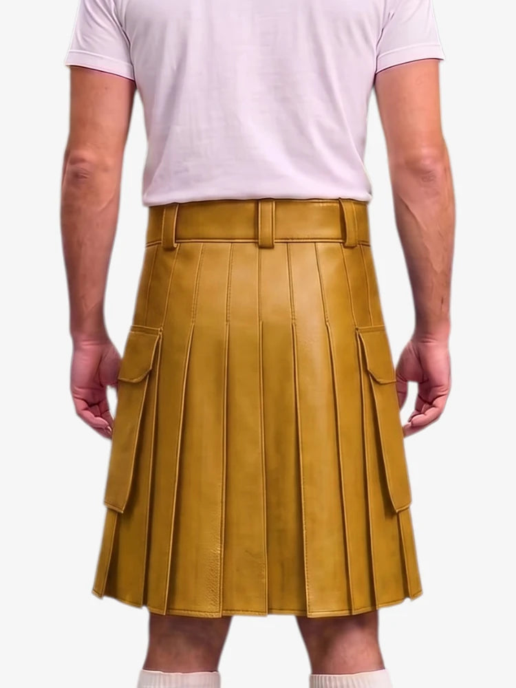 A mustard yellow pleated faux-leather kilt with side cargo pockets, shown on a model from the back wearing a light pink t-shirt and white socks against a light gray background.
